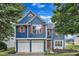 Charming blue two-story home featuring a two-car garage and contrasting orange shutters, set against a vibrant blue sky at 503 Bellmeade Bay Dr, Durham, NC 27703