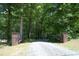 Private gated entrance featuring brick pillars and a gravel driveway lined by mature trees at 5464 Bass Mountain Rd, Snow Camp, NC 27349