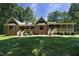 Backyard view of the brick home with a lush lawn and a covered porch at 5464 Bass Mountain Rd, Snow Camp, NC 27349