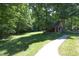 Exterior view of charming outbuilding nestled among mature trees with a concrete walkway at 5464 Bass Mountain Rd, Snow Camp, NC 27349