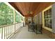 Covered porch with wood ceiling, fan, and view of the surrounding trees at 5464 Bass Mountain Rd, Snow Camp, NC 27349