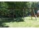 Wooden swing set in a large, lush backyard, perfect for Gathering fun and outdoor activities at 5464 Bass Mountain Rd, Snow Camp, NC 27349