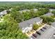 Aerial view of townhomes with ample parking and mature trees in a lush, green community under a clear blue sky at 5717 Corbon Crest Ln, Raleigh, NC 27612