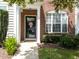 Charming townhome entrance featuring a brick facade, well-manicured bushes and a cheery front door at 5717 Corbon Crest Ln, Raleigh, NC 27612