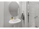 Stylish powder room featuring a pedestal sink, round mirror, and modern fixtures at 627 Georgias Landing Pkwy, Raleigh, NC 27603