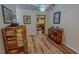 Hallway with wood laminate flooring, bookshelf, and doorway leading to the living room at 6305 Holly Ridge Rd, Rougemont, NC 27572
