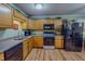Traditional kitchen with wood cabinets, black appliances, and a stainless steel sink at 6305 Holly Ridge Rd, Rougemont, NC 27572