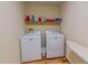 Bright laundry room with hardwood floors, washer, dryer, shelving and space-saving ironing board at 6305 Holly Ridge Rd, Rougemont, NC 27572