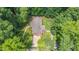 An aerial view reveals a brick home nestled among lush trees with a long driveway at 712 Orange High School Rd, Hillsborough, NC 27278