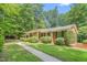 A view of the side of the charming brick home with a lush landscaped yard and a stone walkway at 712 Orange High School Rd, Hillsborough, NC 27278