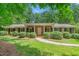 Charming brick home featuring a well-manicured lawn, lush landscaping, and a welcoming front entrance at 712 Orange High School Rd, Hillsborough, NC 27278