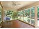 Enclosed sunroom with ceiling fan, brick flooring, and window views of wooded backyard at 712 Orange High School Rd, Hillsborough, NC 27278