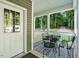 Charming covered porch with patterned rug and seating offers a tranquil view of the property and driveway at 8226 Mcarthur Park Dr, Efland, NC 27243