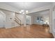 Open-concept living room with hardwood floors, a staircase, and a decorative chandelier enhancing the bright atmosphere at 1040 Bellenden Dr, Durham, NC 27713