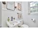 Bathroom features pedestal sink, white wainscoting and trim, with a window view to the exterior at 1104 Englewood Ave, Durham, NC 27701