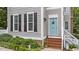 Close-up of the front door with its blue color, charming wreath, and black shutters of the nearby windows at 124 Kingsport Rd, Holly Springs, NC 27540