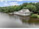Lake house with a large covered porch and a private dock for fishing and boating, surrounded by water and lush trees at 124 Kingsport Rd, Holly Springs, NC 27540