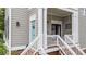 Cozy front porch showcasing outdoor furniture, a striped pillow, and a decorative welcome sign on the front door at 124 Kingsport Rd, Holly Springs, NC 27540