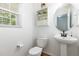 Cozy bathroom with a pedestal sink, toilet, and window for natural light at 128 Palmdale Ct, Holly Springs, NC 27540