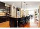 Open kitchen with a large island featuring bar stools, stainless steel appliances, and dark wood cabinets at 150 Saint Mellion St, Raleigh, NC 27603