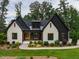 Charming, modern home with a combination of white-painted brick and black accents and lush front yard landscaping at 153 W Beech Slope Ct, Chapel Hill, NC 27517