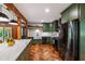 Modern kitchen featuring herringbone floors, dark green cabinetry, a farmhouse sink, and stainless steel appliances at 1606 Sycamore St, Durham, NC 27707