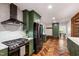 Bright kitchen featuring green cabinets, stainless steel appliances, and beautiful herringbone wood flooring at 1606 Sycamore St, Durham, NC 27707