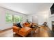 Bright living room featuring an orange sectional couch, hardwood floors, and large windows with wooded views at 1606 Sycamore St, Durham, NC 27707