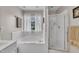 A white tiled bathroom featuring a soaking tub, shower, and bright natural light at 171 St. Jiles Dr, Clayton, NC 27520