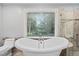 Bright bathroom with clawfoot tub, walk-in shower with glass door, and a large window overlooking nature at 202 Stoneleigh Dr, Cary, NC 27511