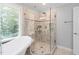 Bathroom with a modern glass-enclosed shower, a clawfoot tub, and a large window for natural light at 202 Stoneleigh Dr, Cary, NC 27511