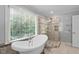 Bathroom featuring a luxurious clawfoot tub and glass-enclosed shower with detailed tile work and natural light at 202 Stoneleigh Dr, Cary, NC 27511
