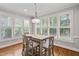 Bright dining room featuring a wood table, decorative lighting, and large windows with plantation shutters at 202 Stoneleigh Dr, Cary, NC 27511