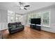 Bright living room with hardwood floors, modern ceiling fan, ample windows and open view to kitchen at 202 Stoneleigh Dr, Cary, NC 27511