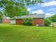Expansive backyard featuring a well-maintained lawn, mature trees, and the rear view of the brick home at 218 Forestville Rd, Wake Forest, NC 27587