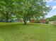 Expansive backyard featuring a well-maintained lawn, mature trees, and the rear view of the brick home at 218 Forestville Rd, Wake Forest, NC 27587