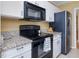 Open-concept kitchen features stone counters, white cabinets, and black appliances at 224 Kirkwood Dr, Chapel Hill, NC 27514