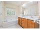 Well-lit bathroom featuring a soaking tub, double sinks, and a large mirror at 2241 Spruce Shadows Ln, Raleigh, NC 27614