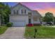Inviting two-story home with a manicured lawn, attached garage, and charming front porch bathed in the warm glow of sunset at 2241 Spruce Shadows Ln, Raleigh, NC 27614