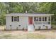 Charming brick home with a vibrant red front door and covered porch, surrounded by lush greenery at 2702 Red Valley Dr, Rougemont, NC 27572