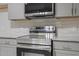 Modern stainless steel stove and microwave against a tiled backsplash and gray cabinets at 2702 Red Valley Dr, Rougemont, NC 27572