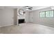Cozy living room with fireplace, ceiling fan, and natural light from the large window at 2905 Scuppernong Ln, Durham, NC 27703