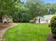 Green backyard and charming home with white siding, green metal roof, and lush landscaping at 300 Oak Ridge Dr, Hillsborough, NC 27278