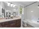 Bright bathroom with a large mirror, vanity, tiled tub, and modern fixtures at 300 Oak Ridge Dr, Hillsborough, NC 27278