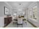 Formal dining room featuring wainscoting, modern chandelier, and a view into the kitchen at 300 Oak Ridge Dr, Hillsborough, NC 27278
