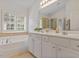 Bright bathroom with double vanity, soaking tub, separate shower, and shuttered windows for natural light at 3217 Ranbir Dr, Durham, NC 27713