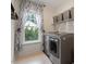 Laundry room with gray front-loading washer and dryer and a window with patterned curtains at 3217 Ranbir Dr, Durham, NC 27713