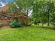 Charming brick home exterior with lush front lawn, mature trees, and blue flowering shrubbery at 3516 Swift Dr, Raleigh, NC 27606