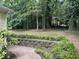 A lovely brick patio with lush landscaping borders a large wooded backyard, offering plenty of privacy at 3517 Eden Croft Dr, Raleigh, NC 27612