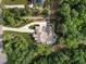 Aerial view of the property showcasing the house, long driveway, lush landscaping, and wooded surroundings at 387 Riverstone Dr, Pittsboro, NC 27312